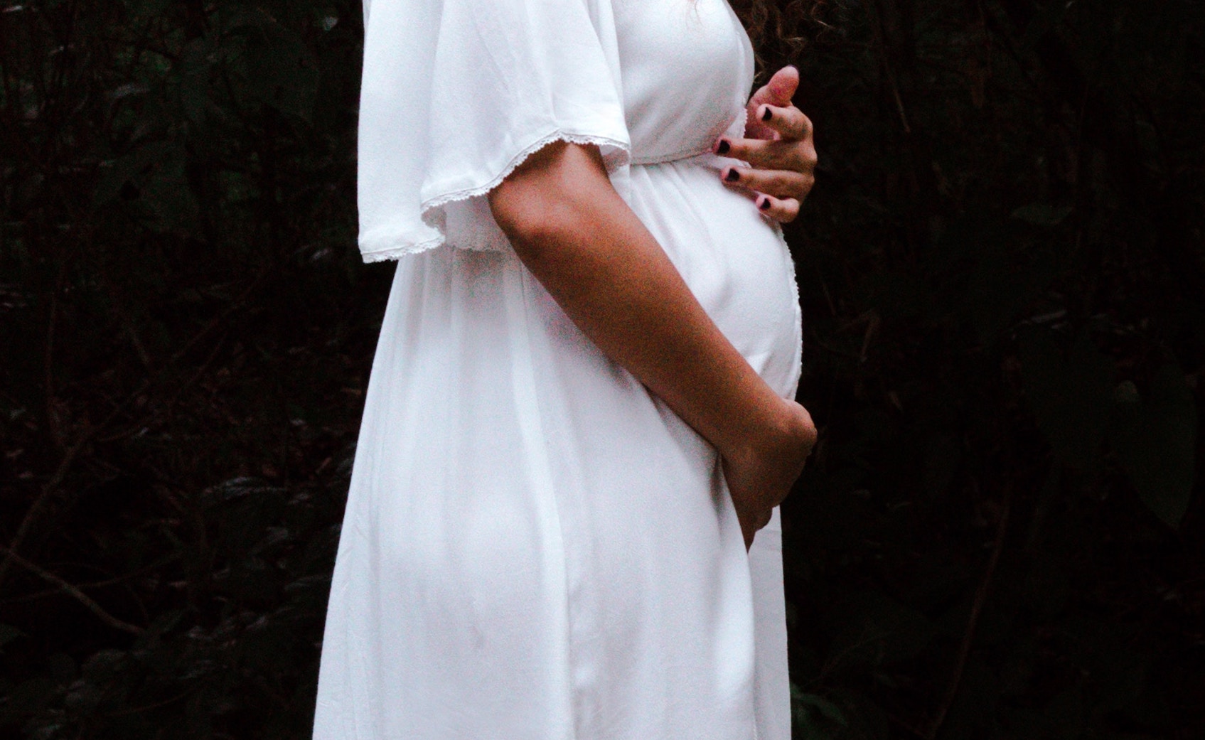 Woman in white dress with baby bump