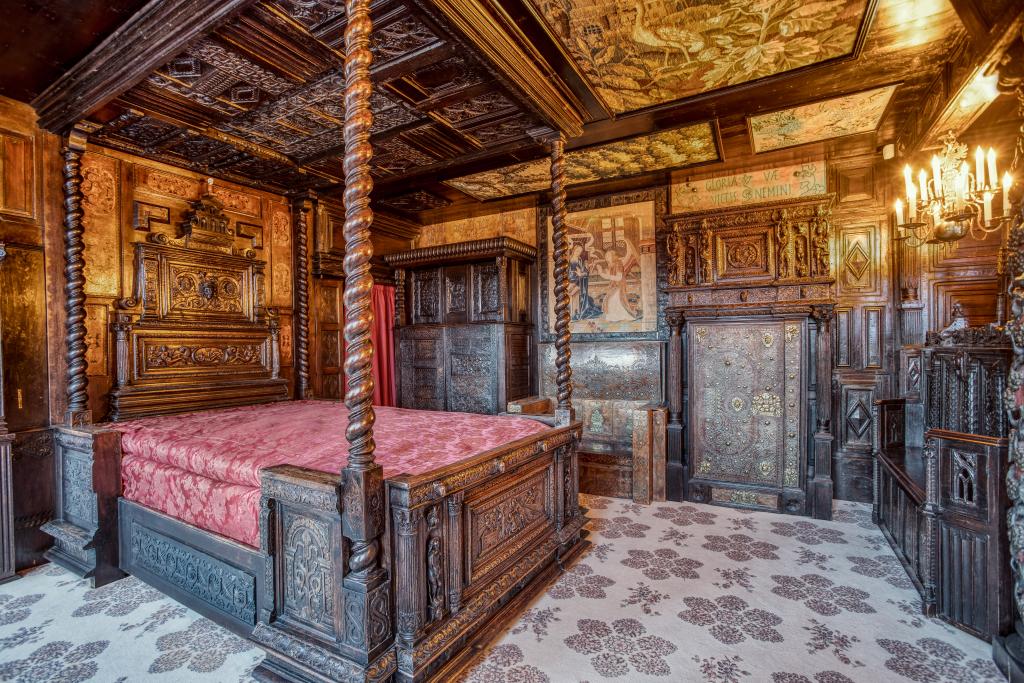 Bedroom featuring intricately carved wood on the walls, ceiling, bedposts, and headboard
