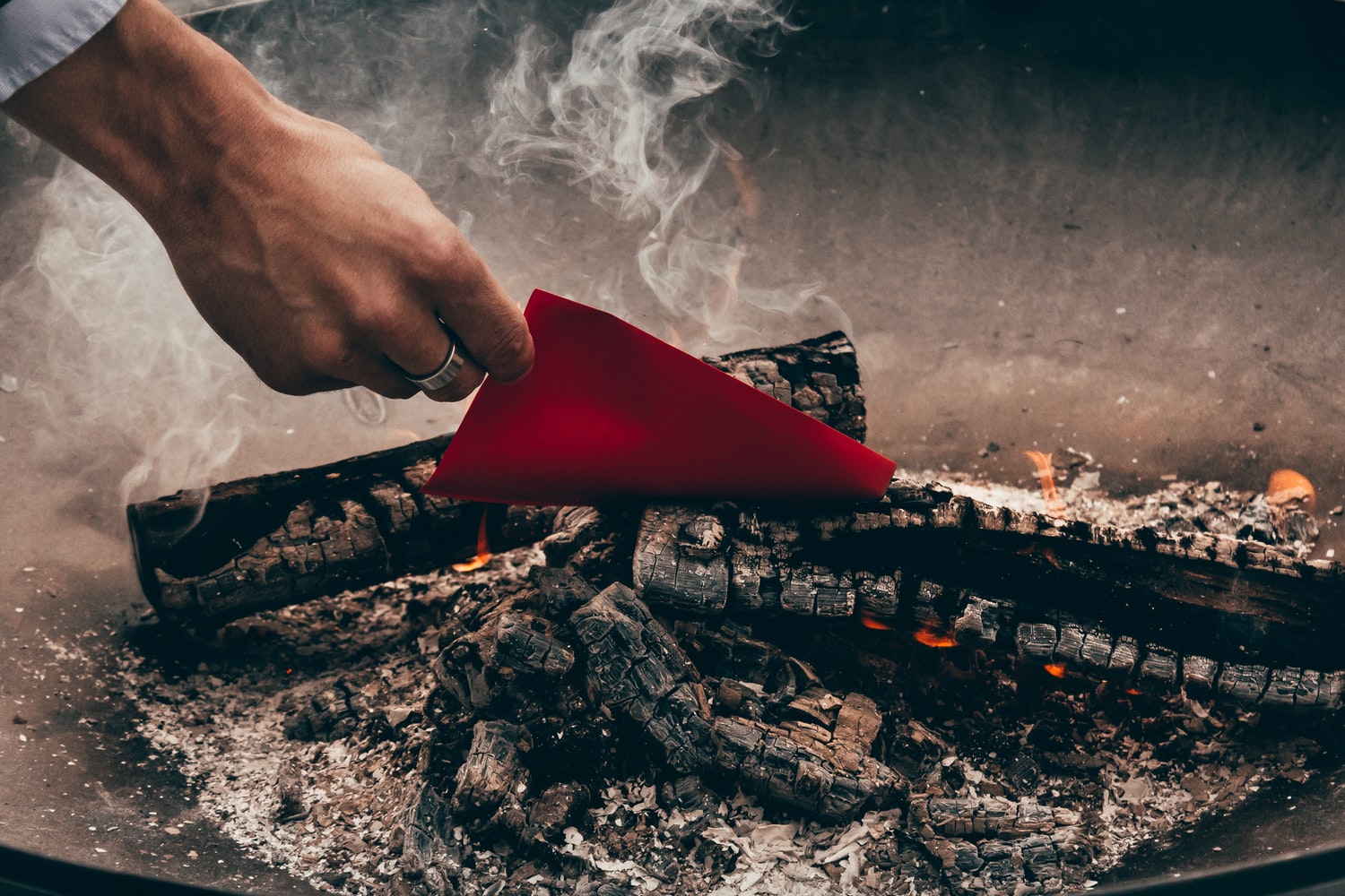 hand putting red paper into fire