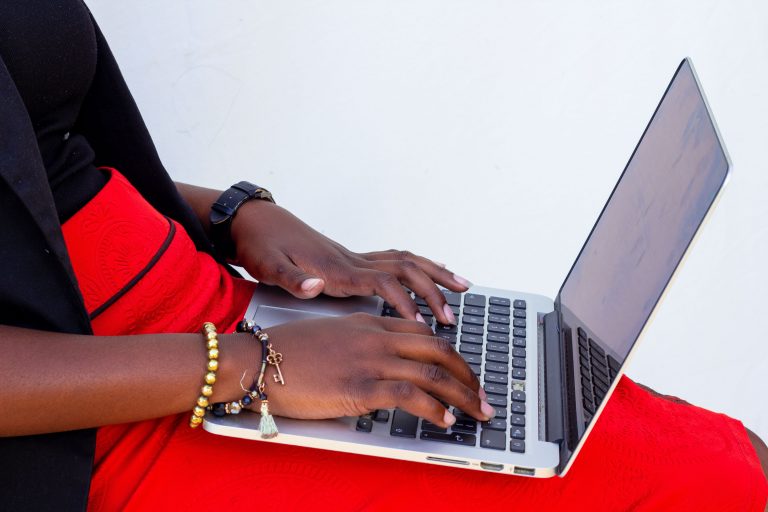 Black woman in bright red skirt typing on a laptop