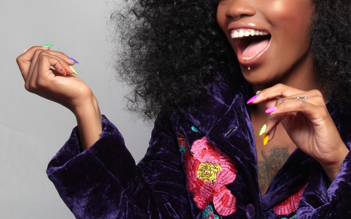 Black woman in colorful dress with colorful nails