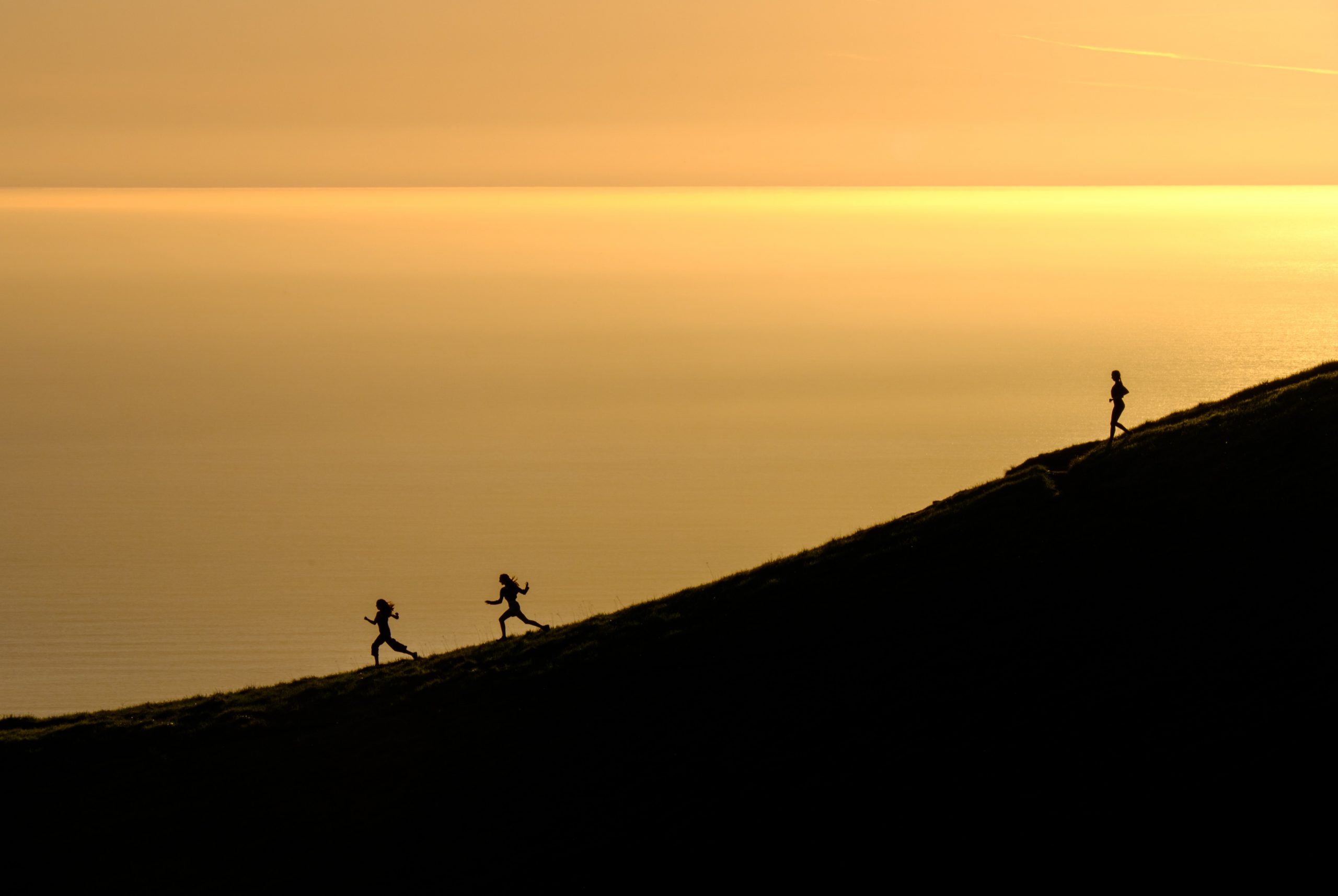 Three people running down a hill