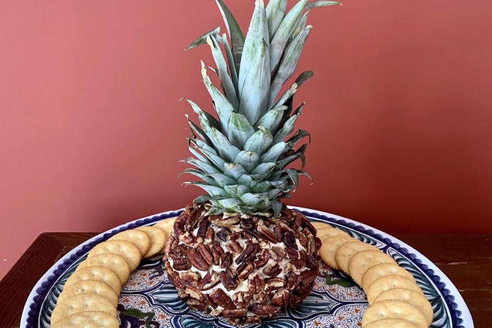 Cheese ball in the shape of a pineapple surrounded by crackers