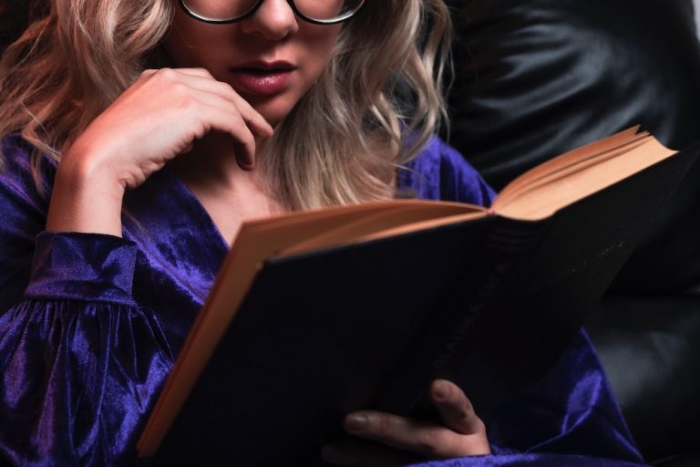 A woman in a purple satin bathrobe reading a book