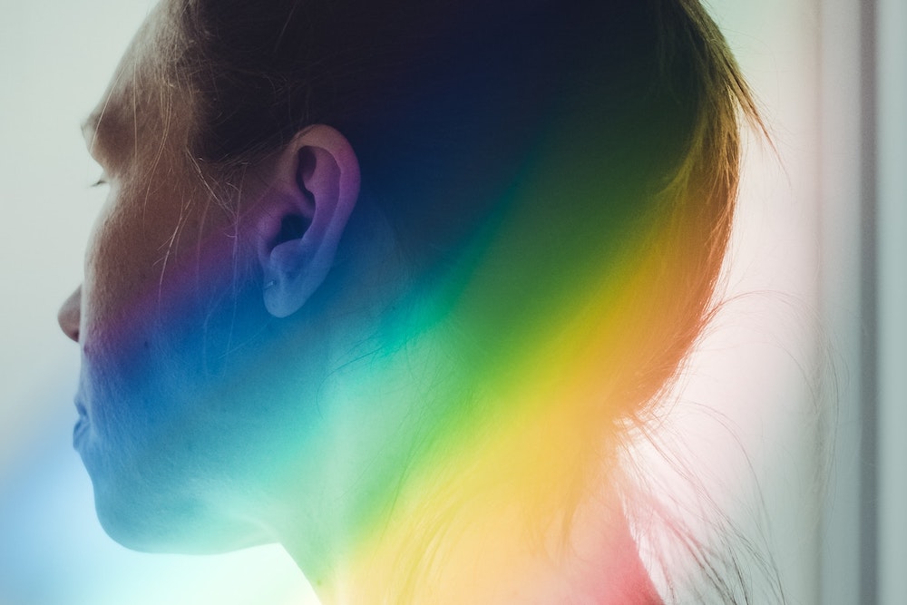 Person looking away from camera with a rainbow beside their head