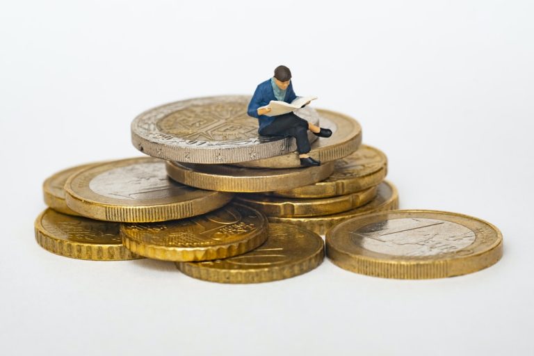 Toy person sitting on pile of coins