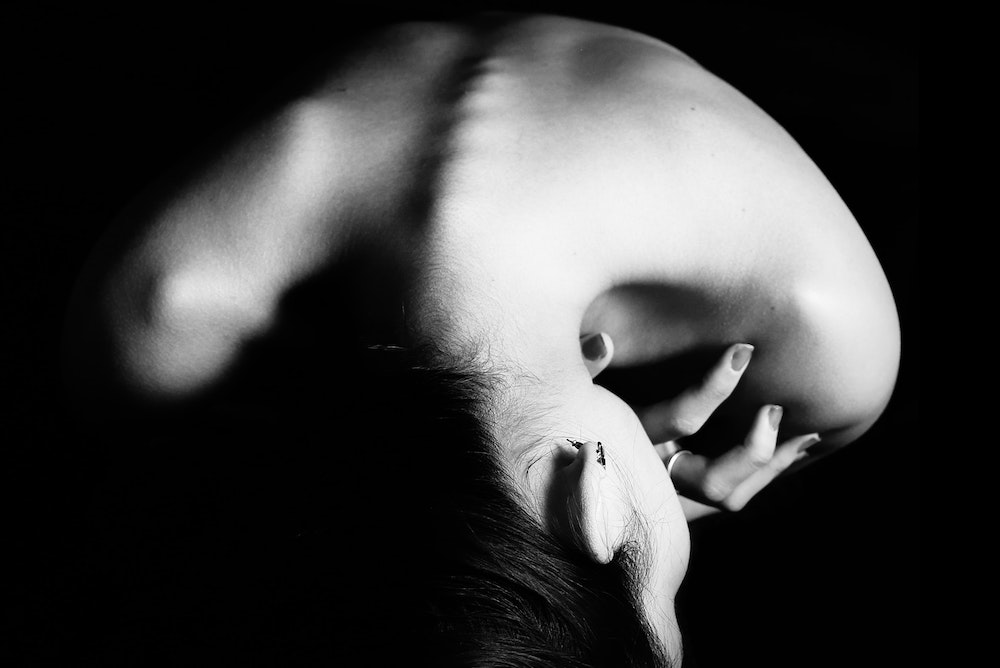 Black and white photo of feminine head, neck, and shoulders, seen from above so that it resembles an abstract shape
