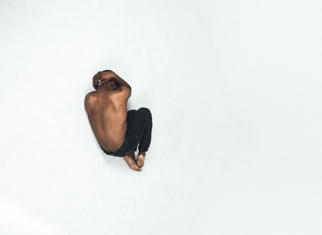 Man curled in fetal position against white background