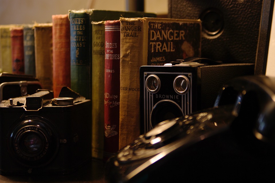 Old, classic books next to vintage looking cameras