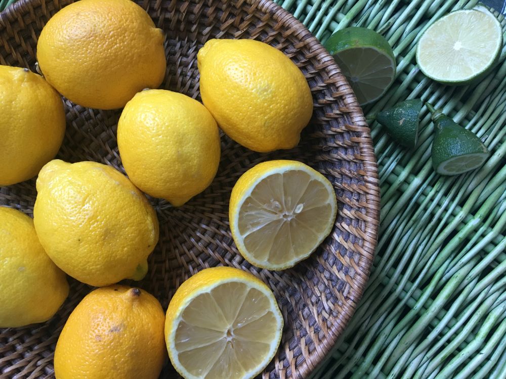 A basket of lemons, several cut open, in a wicker basket on a green table