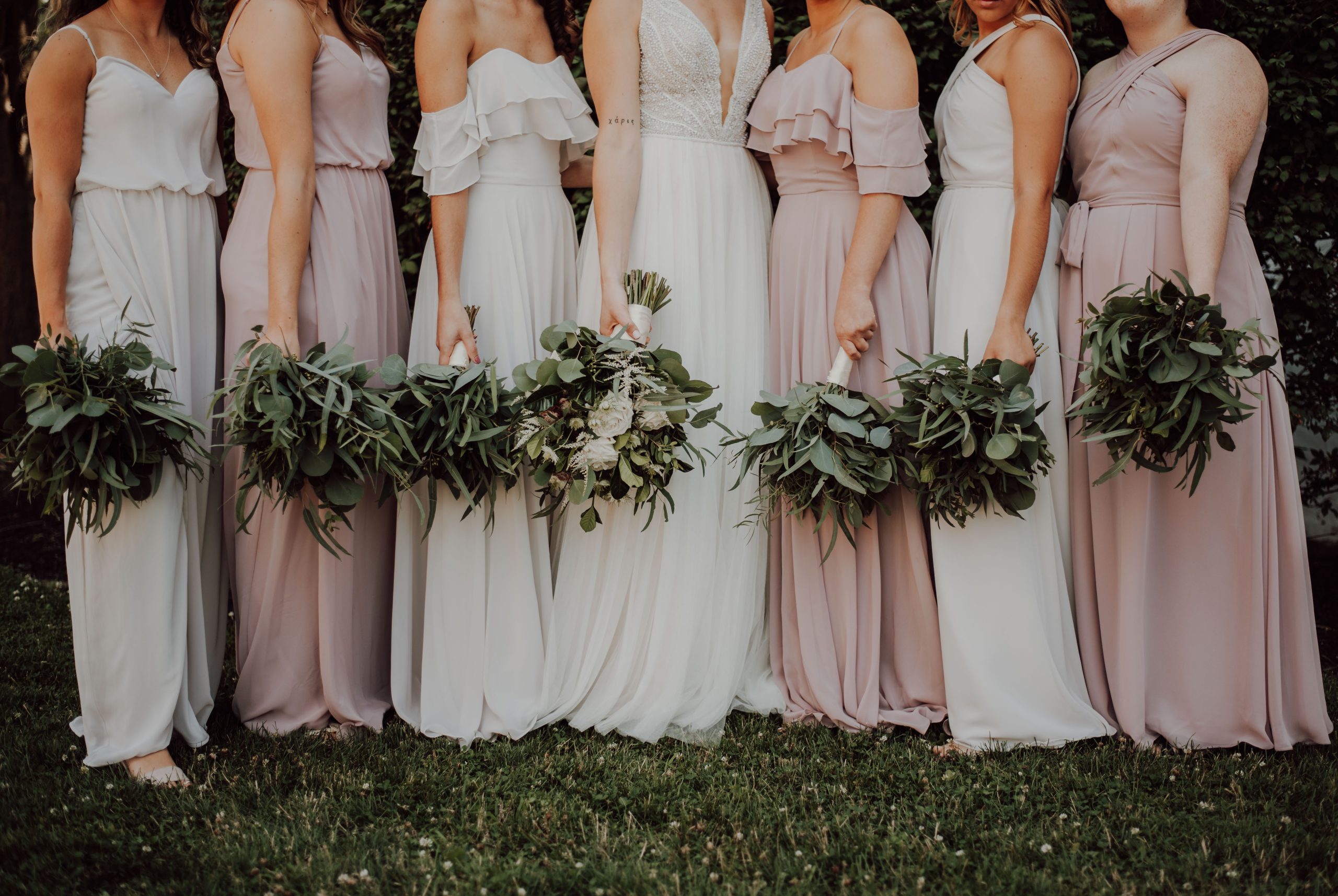 A group of bridesmaids stand in line, oriented towards a bride in the center