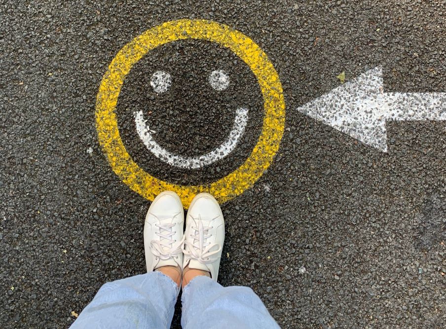 Feet stand on smiley face painted pavement