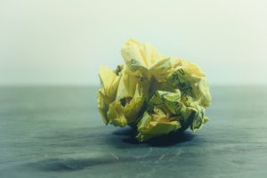 A crumpled piece of yellow paper on a desk.