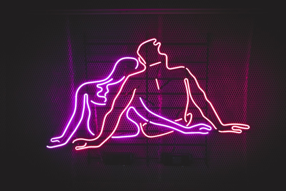 Neon couple cuddling in pink and magenta lighting