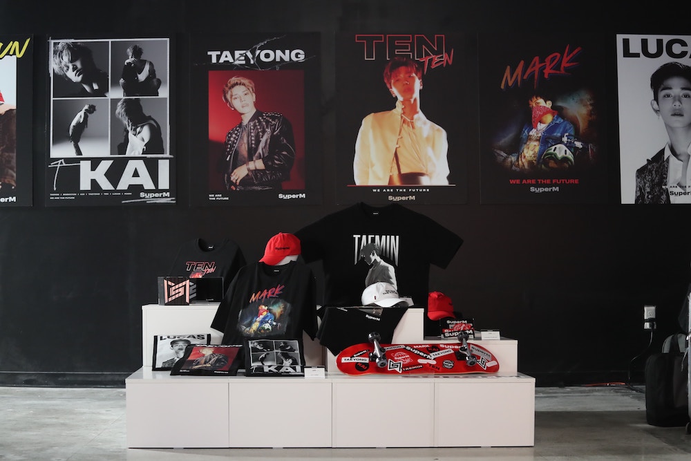 K-pop band merch and posters of the artists on the wall behind