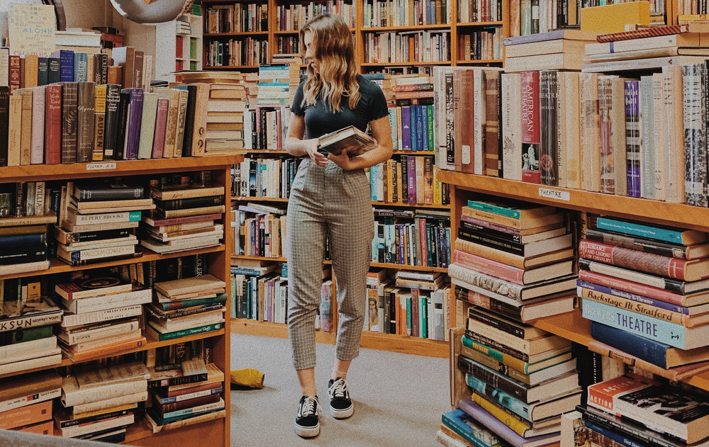 A woman browses a bookstore with a book in her hand.