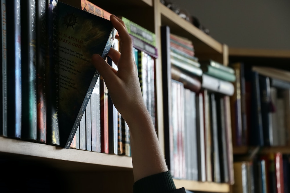 Hand reaching for book in shelf