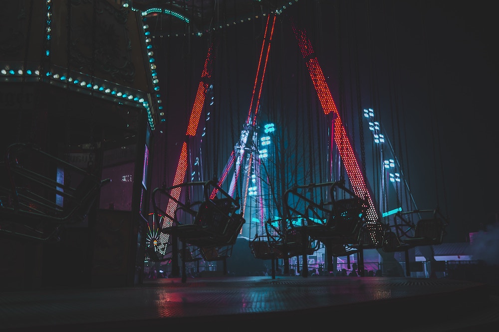Amusement park at night with lit up ride in red and swinging chairs