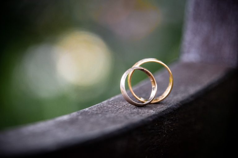 A silver ring and a gold ring standing upright against each other