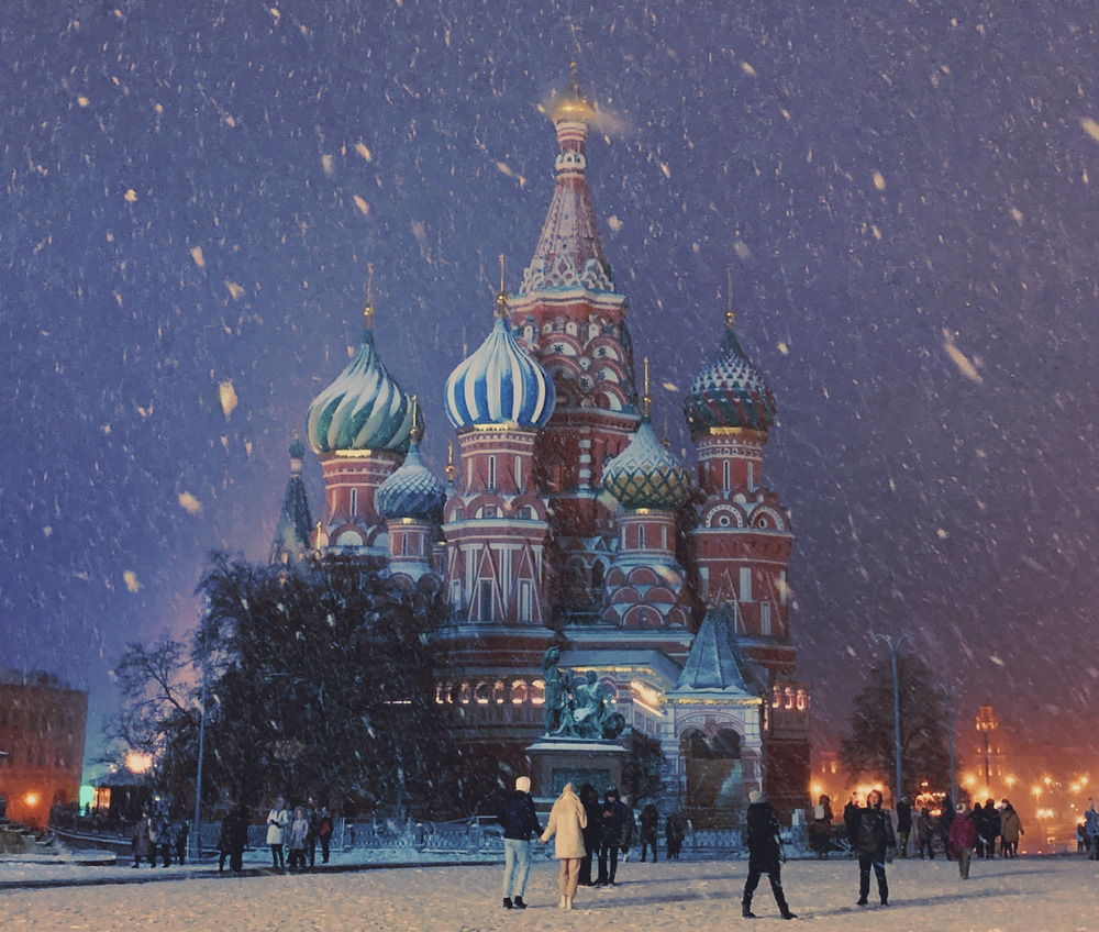 A group of people walk in the snow in front of a church in Moscow, Russia