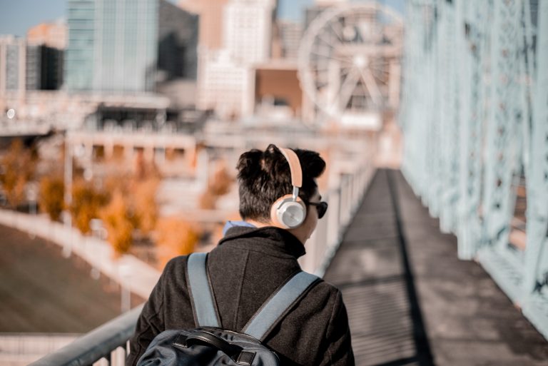 A man wearing headphones walking over a bridge