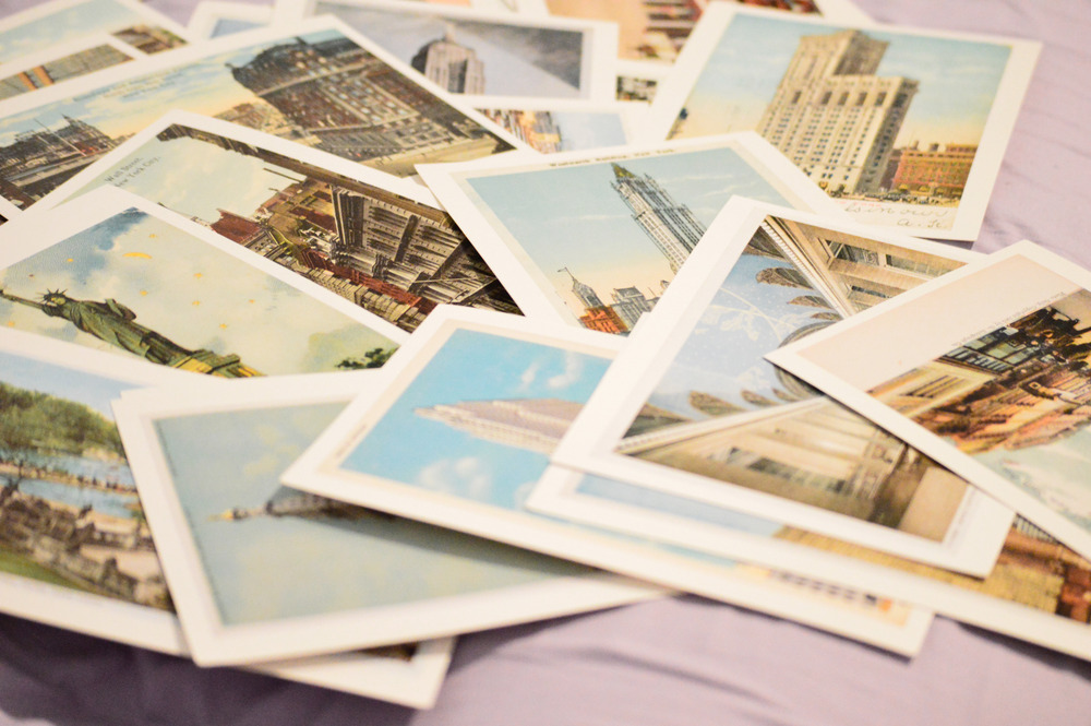 A stack of various postcards lays on a bed