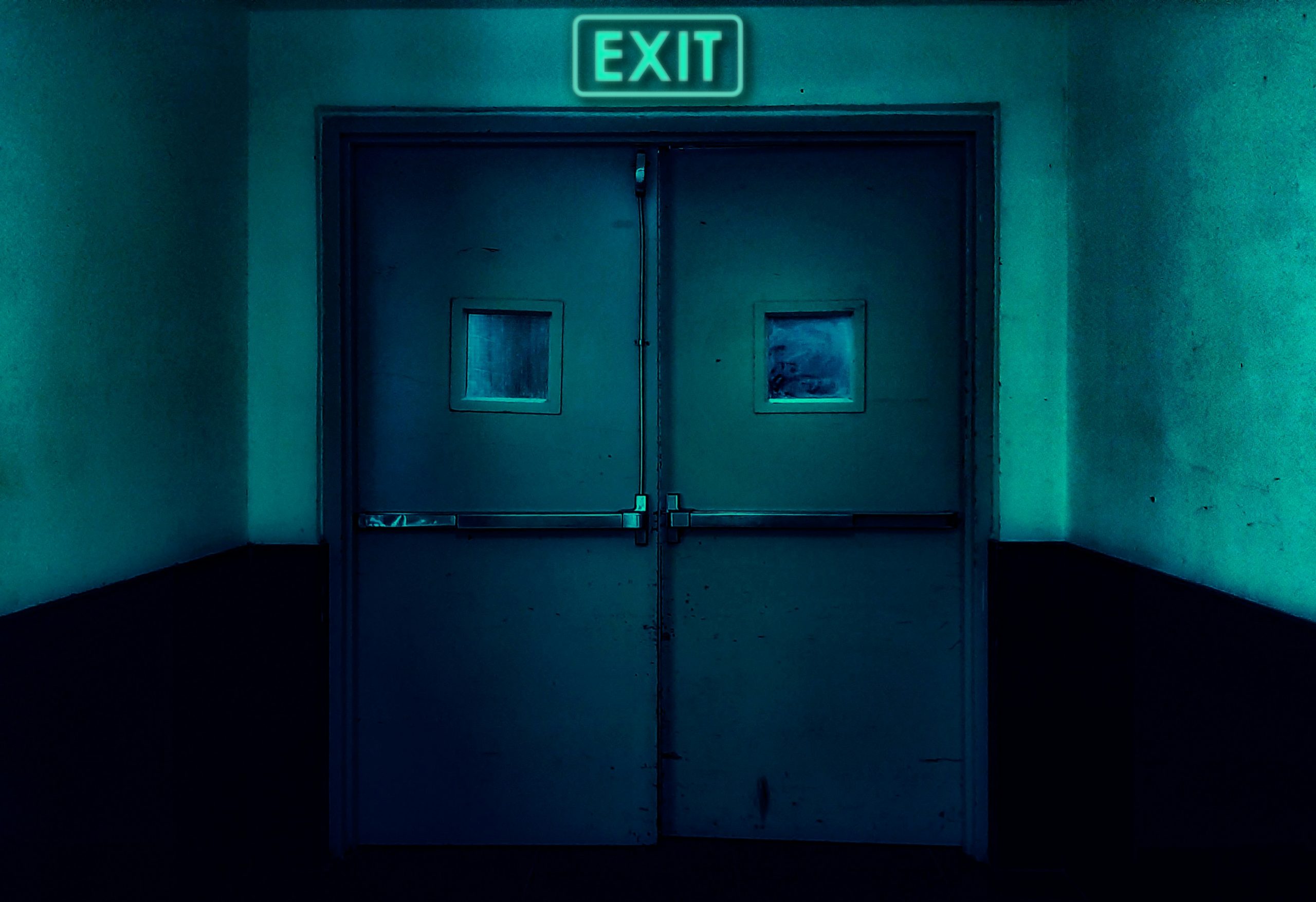 A doorway with an exit sign in the dark