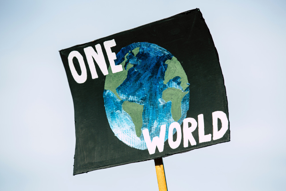 A poster of the Earth with the words "One World" at a climate change protest