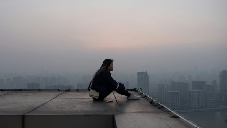 A woman sits on the roof of a skyscraper in Shanghai, China